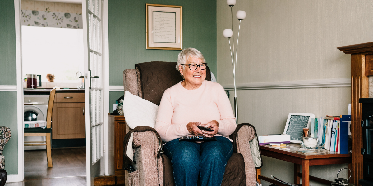 A smiling elder woman in her living room.